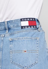 Hellblaue Jeans aus Denim mit sichtbarem weißen, roten und marineblauen "TOMMY JEANS"-Etikett am Bund und kleinem Logo auf der Gesäßtasche.