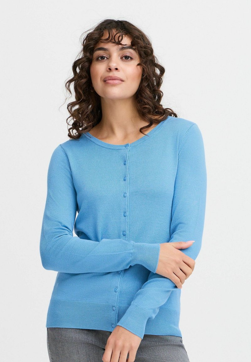 Cardigan bleu clair en tissu fin tricoté. Doté d'un col rond, d'une fermeture à boutons et de manches longues avec des poignets côtelés.