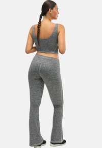 Top corto atlético gris y leggings acampanados de tela texturizada. El conjunto presenta costuras suaves y está diseñado para ofrecer comodidad y flexibilidad.