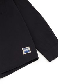 Zwarte langemouwen shirt van katoen met een patch met blauwe graphics en tekst. Heeft een button-down kraag en gestikte manchetten.
