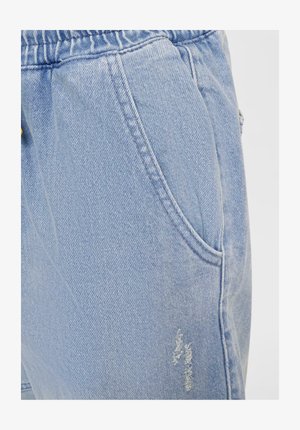 Pantalon en denim bleu clair avec une taille élastique, poches latérales et détails déchirés sur le tissu pour un look décontracté.