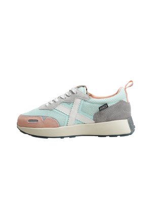 Zapatilla deportiva azul clara con cordones blancos, logo blanco, detalles en ante rosa en la puntera y el talón, y suela beige, vista lateral sobre fondo blanco.