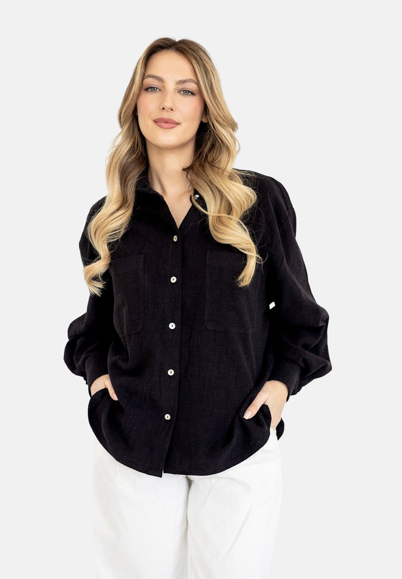 Czarna koszula z guzikami z przodu, z dwiema kieszeniami na piersi, wykonana z teksturowanej tkaniny. Ma luźny krój i lekko obszerne rękawy.