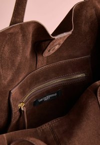 Brown suede handbag with a spacious interior, featuring a zippered pocket, gold zipper, and a branded label inside.