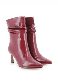 Botas de tobillo de cuero burdeos con un diseño arrugado, punta afilada y tacón delgado. Presentan una textura suave y un detalle de hardware mínimo.