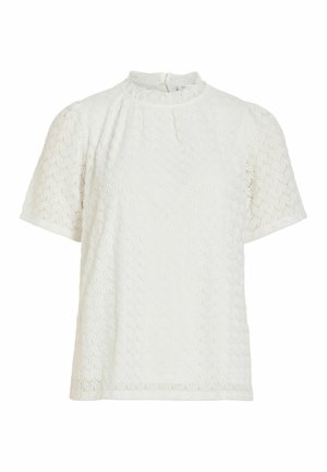 Blouse blanche à manches courtes avec motif circulaire texturé, col montant à volants et fermeture boutonnée au dos.