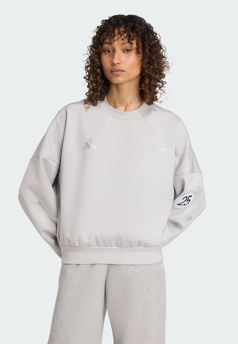 Ljusgrå sweatshirt med rund halsringning, nedsänkta axlar och ribbad nederkant. Har reflekterande detaljer och en logga på bröstet och ärmen.