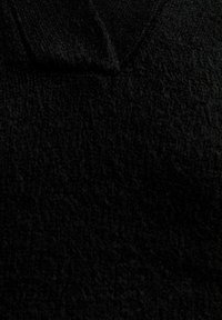 Tessuto nero lavorato a maglia con una texture morbida. Presenta un design a scollo a V e dettagli discreti sulla superficie, mostrando un colore uniforme e scuro in tutto.