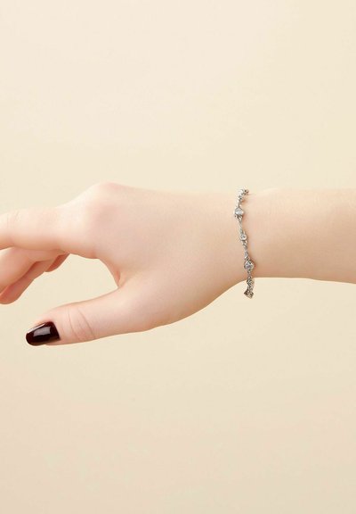 Pulsera de cadena de plata con eslabones decorativos y pequeños charms, que muestra una textura suave y un diseño elegante.