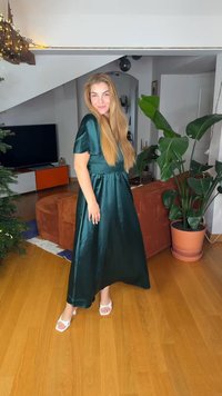 Dlouhé zelené saténové šaty s krátkými rukávy, přiléhavým pasem a splývavou sukní. Nosit je s bílými podpatky, v obývacím pokoji s rostlinami.