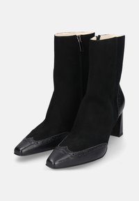 Zwarte enkellaarsjes met een suède bovenwerk, puntige leren neus, zijrits en blokhak met decoratieve stiksels langs de rand.