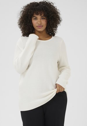 White ribbed long-sleeve sweater with a round neckline and relaxed fit. Soft texture, shown layered over black trousers.