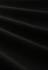 Schwarzer Strickstoff mit einer strukturierten Oberfläche, die weiche, gewellte Falten und ein einheitliches Muster aufweist.