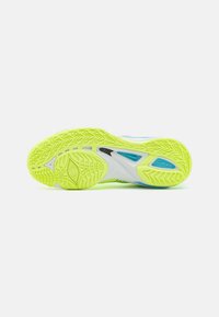 Shoe outsole featuring bright neon yellow rubber with a textured grip pattern, white accents, and a blue detail near the arch.