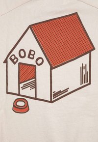 Caseta para perro con techo rojo y un cuenco de comida afuera, con la etiqueta "BOBO" sobre la entrada.