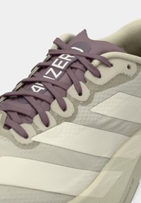 Κοντινή λήψη παπουτσιού τύπου sneaker σε μπεζ και μοβ αποχρώσεις με κορδόνια μοβ και ορατό το κείμενο "BLAZER" στη γλώσσα.