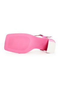 Sandalia de tacón rosa con suela ancha, textura suave, correa ajustable y un tacón blanco contrastante. Presenta ranuras horizontales en la parte inferior.