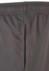 Gros plan d’un short de sport gris foncé montrant une ceinture élastique et un tissu en mesh texturé.