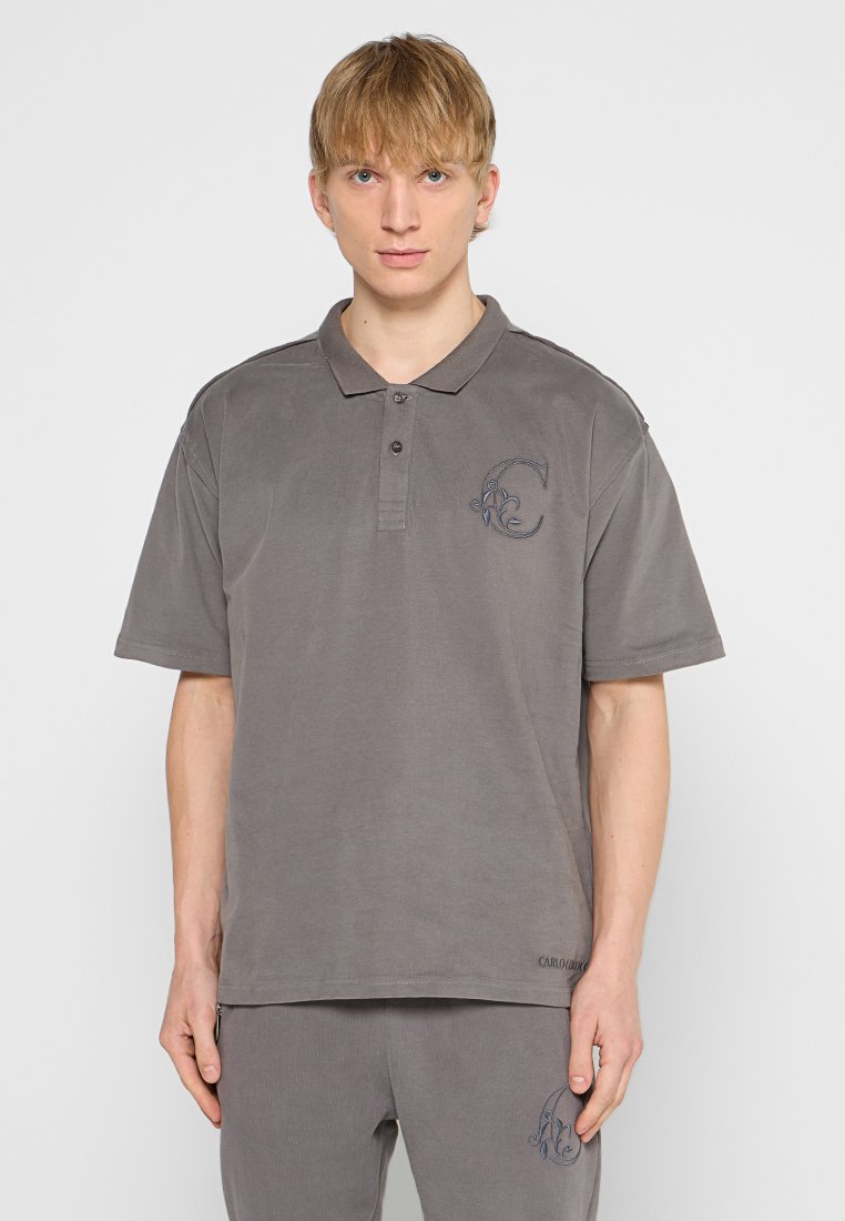 Grijze poloshirt van zacht stof met een klassieke kraag, drie knopen en een geborduurd logo op de linkerborst.
