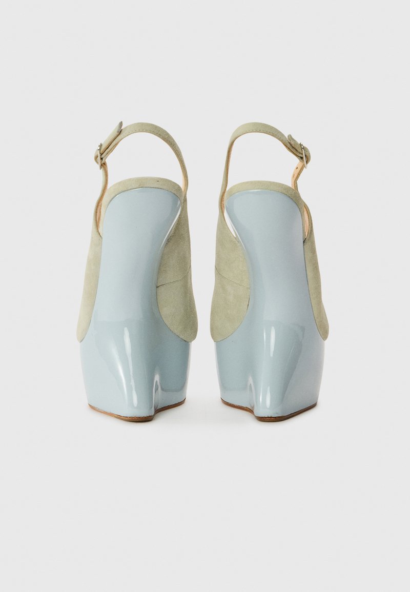 Hochhackige Schuhe mit einem hellblauen glänzenden Obermaterial und sanften grünen Wildlederakzenten, ausgestattet mit offener Ferse und Knöchelriemen zur Unterstützung.