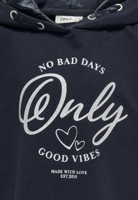 Sudadera azul marina con texto en brillo plateado: "NO HAY DÍAS MALOS," "Solo," y "BUENAS VIBRACIONES," con acentos de corazones. Hecha con amor, establecida en 2015.