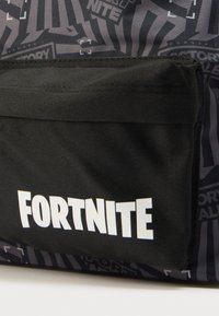 Μαύρο σακίδιο πλάτης με υφή στην επιφάνεια, λογότυπο «FORTNITE» σε έντονα λευκά γράμματα και γκρι σχέδιο με διάφορα γραφικά.
