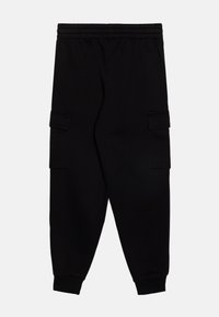 Sorte sweatpants lavet af bomuldsstof med elastisk talje, tætsiddende ben og sidelommer til opbevaring.