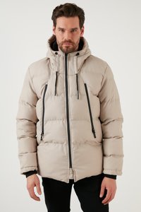Giubbotto imbottito beige con colletto alto, zip nera e dettagli con cordoncino, caratterizzato da una texture trapuntata e due tasche frontali con zip.