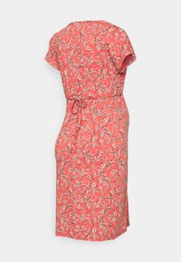 Vestido coral com mangas curtas, padrão floral em branco e preto, cintura cingida, comprimento até ao joelho e fenda lateral para maior liberdade de movimento.