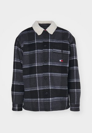 Schwarze und graue karierte Jacke mit einem mit Fell gefütterten Kragen, ausgestattet mit Knöpfen und einer Brusttasche mit einem Logo-Patch. Weicher Stoff.