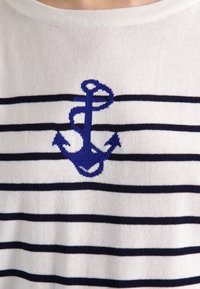 Katoenen T-shirt met horizontale marineblauwe en witte strepen, met een blauwe ankerontwerp gebreid in het midden. Zachte textuur en ronde hals.