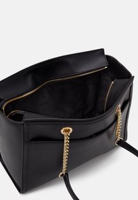 Black leather handbag with gold hardware, zipper closure, and chain accent on straps. Interior features a smooth black lining with branding.