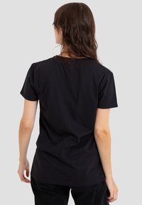 Black cotton T-shirt featuring a simple crew neck, short sleeves, and relaxed fit. The fabric appears smooth with minimal seams.