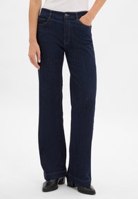 Ciemnoniebieskie dżinsy w szerokim kroju z klasycznym pi�ęciopocketowym wzorem, subtelnymi przeszyciami i zapięciem na guzik w talii.