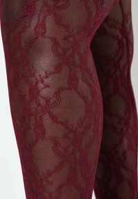 Bordowe koronkowe rajstopy z kwiatowym wzorem, wykonane z przejrzystej siateczki z misternymi zdobieniami na całej tkaninie.