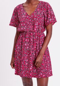 Floral dress in a pink and red pattern with short sleeves, V-neckline, and an elastic waist for a relaxed fit. Lightweight fabric.