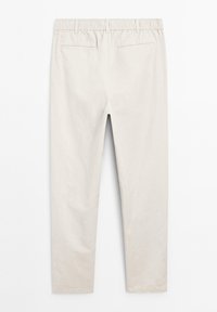 Ljusbeige byxor med elastisk midja, med två bakfickor och en avsmalnande ben-design. Slät tyg med minimala veck.