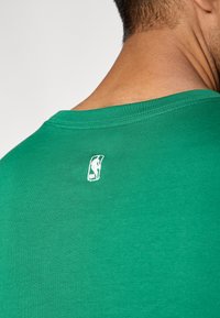Πράσινο βαμβακερό T-shirt με στρογγυλή λαιμόκοψη. Διαθέτει λευκό λογότυπο NBA κεντημένο στην πλάτη. Λείο ύφασμα, απλός σχεδιασμός.