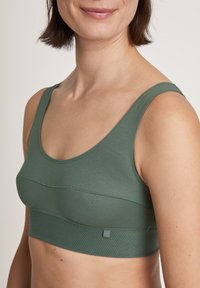 Green, seamless bra with wide straps and a cropped design. Soft fabric with a smooth texture and subtle horizontal stitching detail.