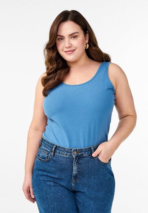 Blue sleeveless top with a round neckline, made from soft fabric, paired with high-waisted dark blue jeans featuring a fitted silhouette.