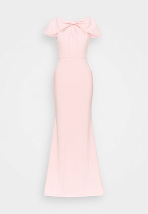 Robe longue rose clair avec détail de large nœud épaules dénudées et silhouette cintrée sur fond uni.