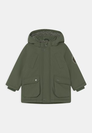 Manteau d’hiver pour enfant à capuche vert olive avec doublure polaire, deux poches frontales à rabat, fermeture par boutons et zip, et un écusson sur la manche gauche.