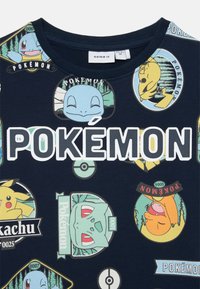 T-shirt in cotone blu navy con diverse grafiche di personaggi Pokémon e una grande scritta bianca "POKÉMON" sul petto.