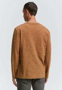 Langsleeve shirt in een gestructureerde, roestkleurige stof, met een ronde hals en een relaxte pasvorm. Achteraanzicht toont platte naden en een casual silhouet.