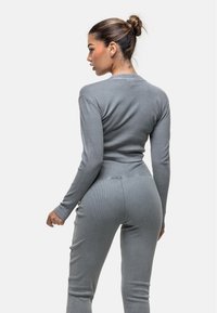 Top a maniche lunghe grigio a costine abbinato a pantaloni aderenti coordinati. Il tessuto ha una texture morbida e un design attillato e aderente.