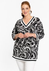 Zwart-witte tuniek met bloemenpatroon, V-hals en 3/4 mouwen, met contrasterende gestreepte manchetten en zoom. Zachte stoftextuur.