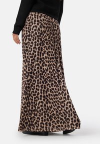 Maxi sukně s leopardím vzorem vyrobená z měkké tkaniny, s hnědobílým a černým vzorem, plynulým designem a páskem, který se pohodlně nosí v pase.