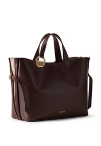 Braune Leder-Shopper-Tasche mit abgerundeten Griffen, goldfarbenem Ringdetail und einer strukturierten Seitenakzentuierung. Zeigt eine minimalistische Markenkennzeichnung auf der Vorderseite.