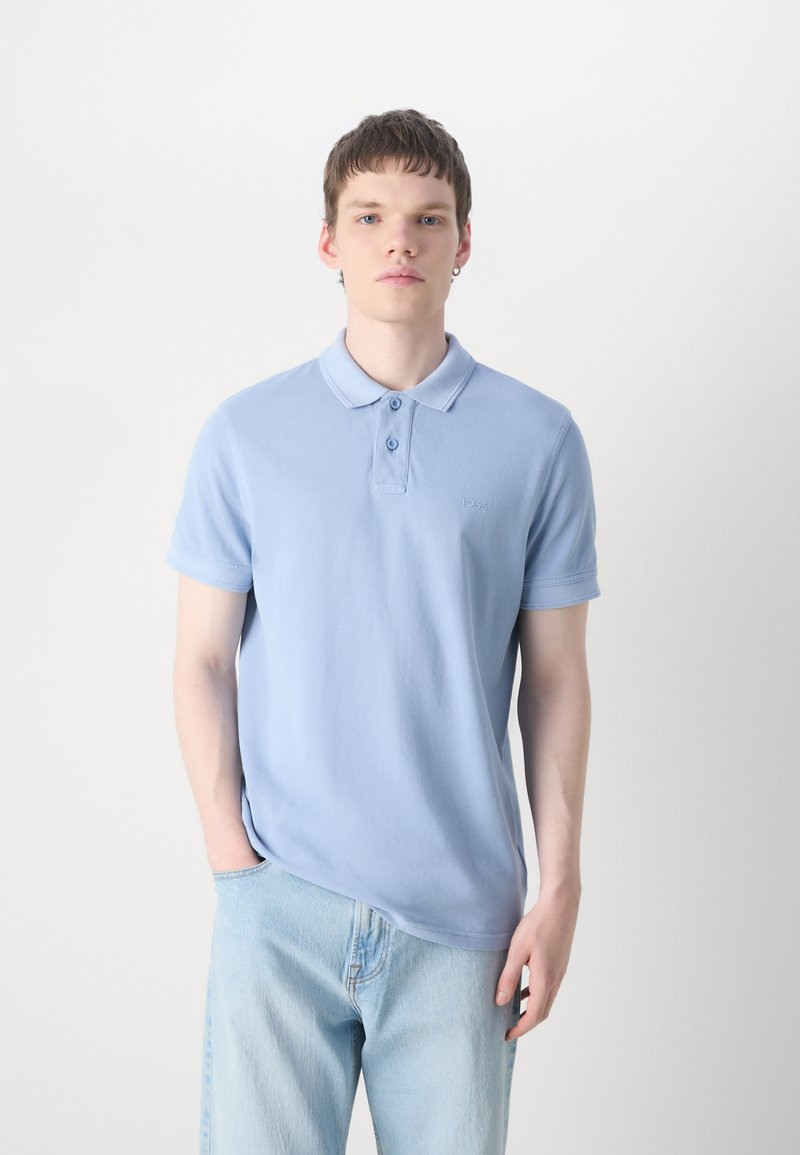 Polo shirt bleu clair en coton doux, doté d'un col classique, d'une patte de boutonnage à trois boutons et d'un logo subtil brodé sur la poitrine.