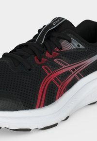 Μαύρο παπούτσι τρεξίματος Asics με κόκκινες και γκρι ρίγες, μαύρα κορδόνια και λευκή σόλα, εμφανίζεται από γωνία μπροστινής πλευράς.